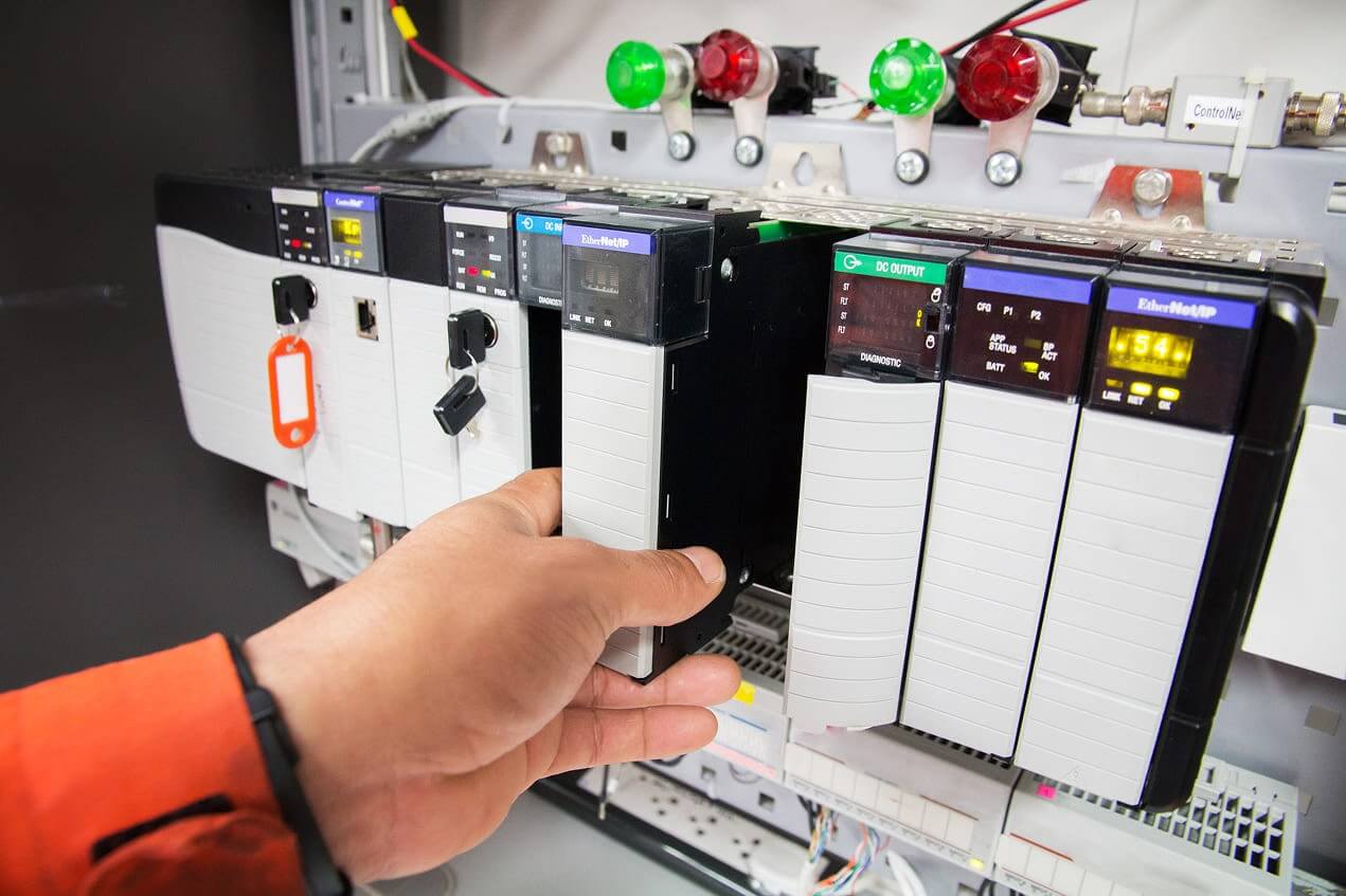 Hand installing a power supply module into a control panel.